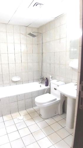 a bathroom with a toilet and a tub and a sink at Dragon Golden Apartment 2 in Dubai