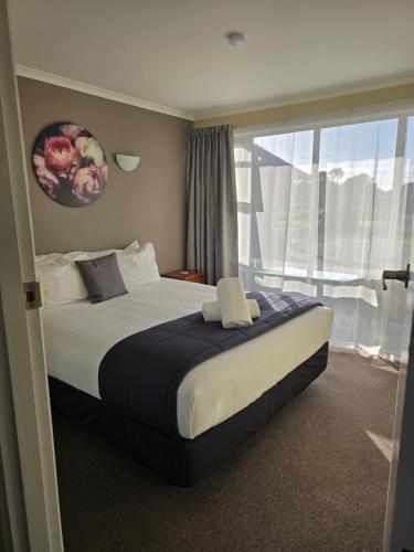 a bedroom with a large bed with a window at Monarch Motel in Invercargill