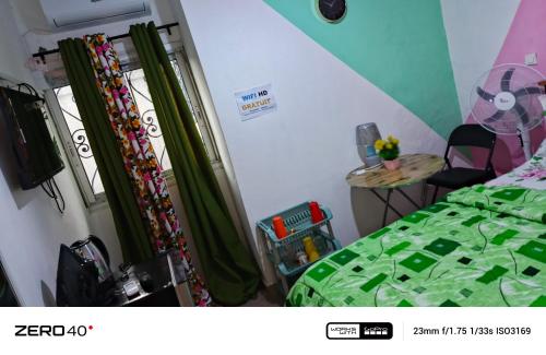 a bedroom with green curtains and a bed and a table at manoir hoome in Bonabéri