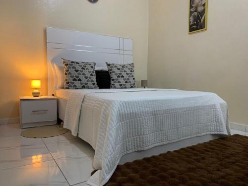 a bedroom with a large bed with a white comforter at Chambre climatisée , wifi , serviettes, café ou thé offert in Dakar
