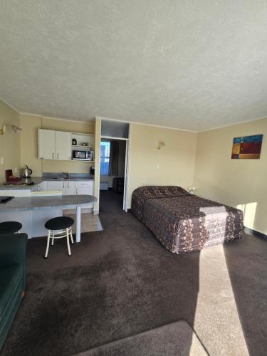 a hotel room with a bed and a kitchen at Monarch Motel in Invercargill