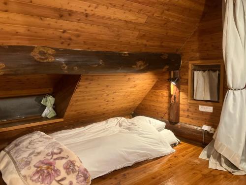 a bed in a room with a wooden wall at Ekinoyado Hirafu in Kutchan