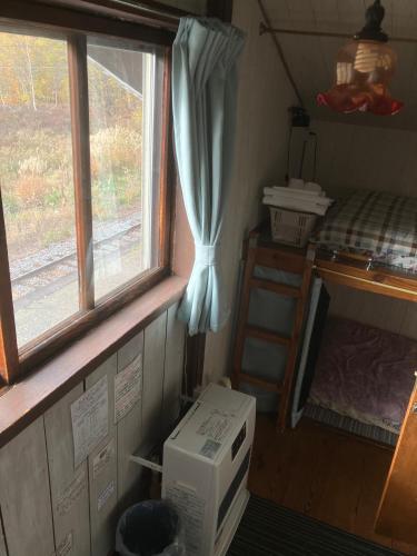 a microwave in a room with a window and a bed at Hirafu Station Guesthouse - Ekinoyado Hirafu in Kutchan