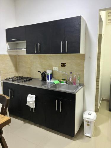 een keuken met zwarte kasten en een spoelbak bij Apartaestudio Suite 201 in Montería
