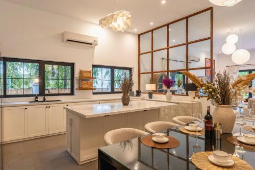 a kitchen with a large island with chairs and tables at Gorgeous Grand 1000m2 Villa - 5BR with pool in D2 by Ray 02 in Ho Chi Minh City