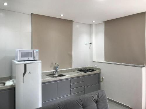 a kitchen with a microwave and a sink and a refrigerator at Apartamento Maravilhoso para Casal em São Roque in São Roque