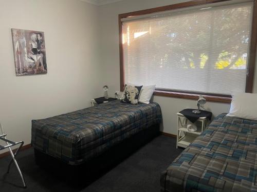 a bedroom with two beds and a large window at Benalla Apartments in Benalla