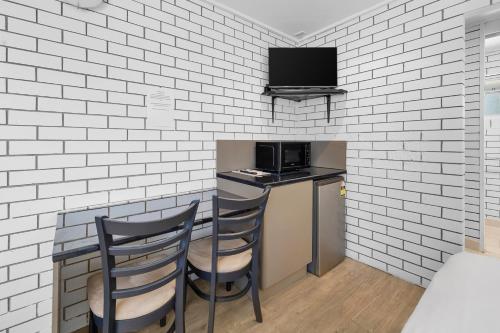 a kitchen with a bar with two chairs and a tv at Pacific Paradise Airport Motel in Pacific Paradise
