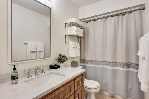 ein Badezimmer mit Waschbecken, Toilette und Spiegel in der Unterkunft White Cedar Retreat in Ellison Bay