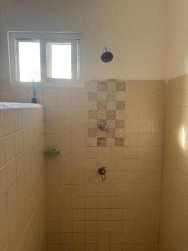 a bathroom with a tiled shower with two windows at Casa Tortuga in Chelem