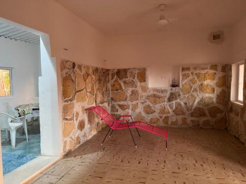 a red chair in a room with a stone wall at Casa Tortuga in Chelem