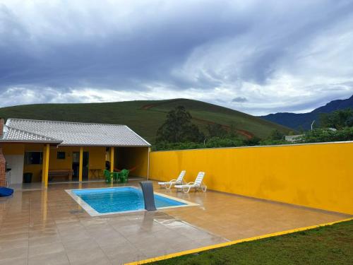 a house with a swimming pool and a yellow wall at Chácara Vista do Pico Agudo in Lavrinhas