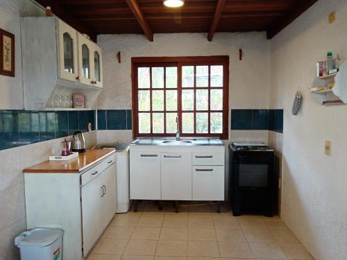 une cuisine avec des armoires blanches, un évier et une fenêtre dans l'établissement La casa del agua, à La Pedrera