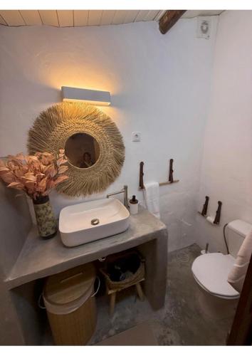 Un baño con lavabo, inodoro y espejo. en Casa Tia Anica I, en Monsaraz