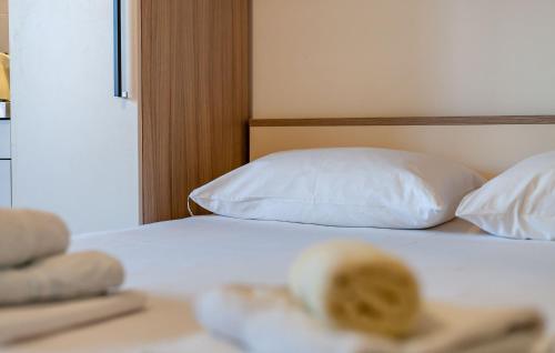 a bed with white sheets and pillows in a room at Apartments and Rooms Dobrila in Jelsa