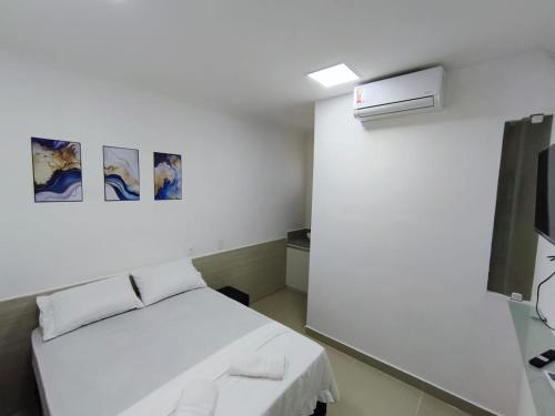 a white room with a bed and some pictures on the wall at Essenza Suites Natal in Natal