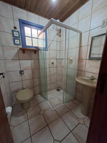 a bathroom with a shower and a toilet and a sink at Casa Sol e Mar in Bombinhas