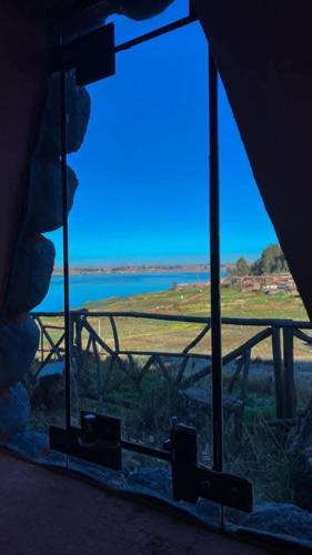 - une fenêtre avec vue sur un champ et l'eau dans l'établissement Cabañas lago piuray, à Chincheros