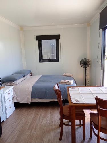 a bedroom with a bed and a table and chairs at Pahoia Pitstop in Tauranga