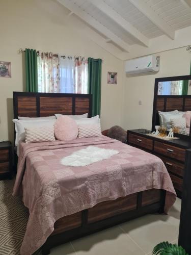 a bedroom with a large bed and a mirror at Home to Comfort in Old Harbour