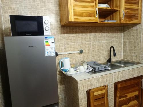 Appartement 3 pièces Tout Confort Calme - Colibri في ياموسوكرو: مطبخ صغير مع ثلاجة ومغسلة