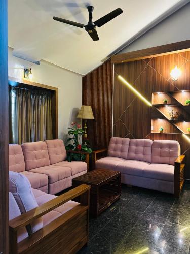 a living room with pink couches and a ceiling fan at The Mallika Holidays in Mananthavady