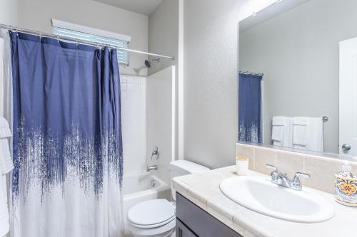 a bathroom with a blue shower curtain and a sink at Nic's Home in Visalia