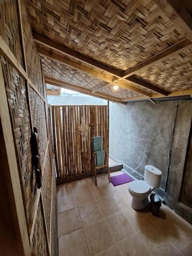 a bathroom with a toilet and a stone wall at Penempuran cottage in Masbagik