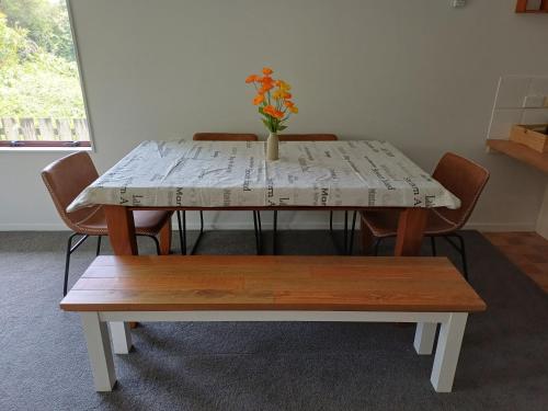 a table with chairs and a vase with flowers on it at House in Restful Setting in Whangarei