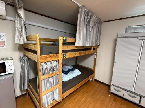 a bunk bed in a room with a refrigerator at Male-only dormitory Tokyo House INN in Tokyo