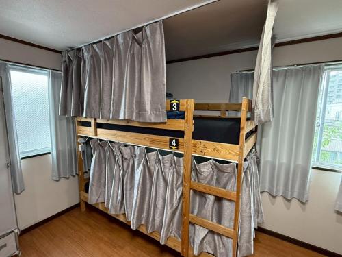 a bunk bed in a room with curtains at Male-only dormitory Tokyo House INN in Tokyo