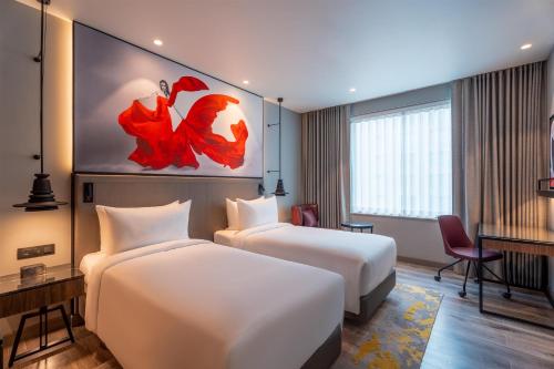 a hotel room with two beds and a desk at Radisson RED Indore in Indore