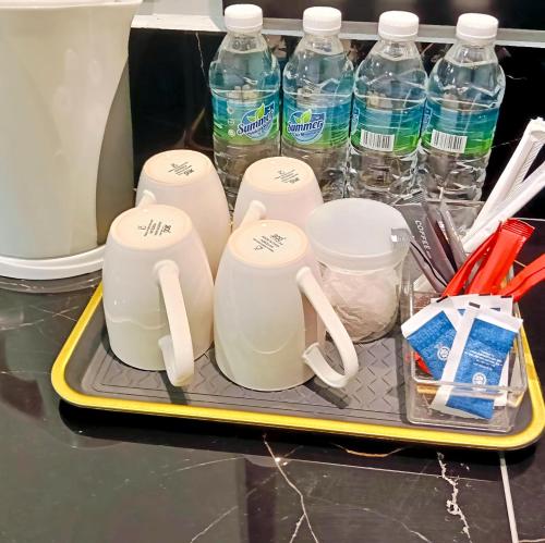 a tray with several cups and bottles of water at KM Barakah Suite in Kuala Terengganu
