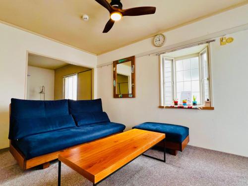 a living room with a blue couch and a table at 江の島HOUSE Comfortable & Relaxing Stay in Fujisawa