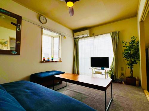 a living room with a blue couch and a table at 江の島HOUSE Comfortable & Relaxing Stay in Fujisawa