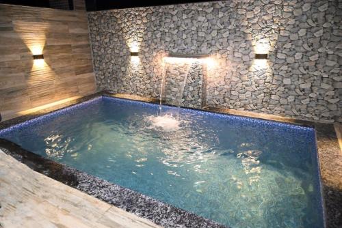 a large swimming pool with a stone wall at Candy Stay's 2BHK with Pvt Pool in Lonavala