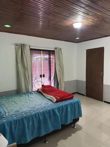 a room with a bed with a blue blanket and a window at Quarto Suite in Mucugê