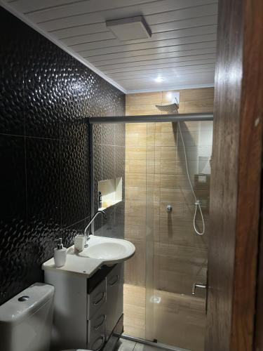 a bathroom with a toilet and a sink and a shower at Quarto Suite in Mucugê