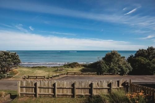 a wooden fence with the ocean in the background at Wow On Wanaka Bay - beachfront living at its best in New Plymouth