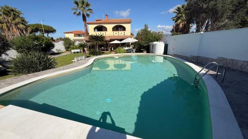 een groot zwembad met een huis op de achtergrond bij Villa Anna in Quartu Sant'Elena