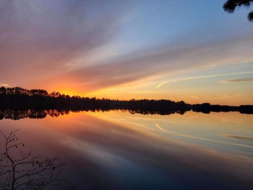a reflection of a sunset on a lake at Idyllic Log Cabin Steps from Somo Lake near Tomahawk, Wisconsin in Tomahawk