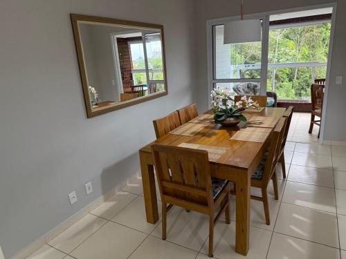 a dining room table with chairs and a mirror at Apartamento em Bertioga, ótima localização, Bertioga Residence Club in Bertioga