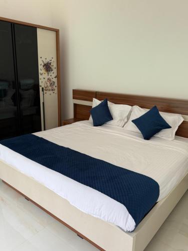 a bedroom with a large bed with blue pillows at KiwiOz Villa in Thamarassery