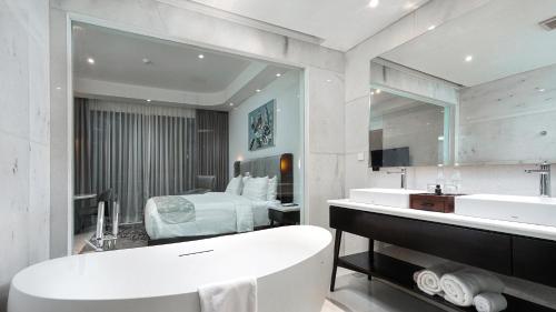 Un baño con bañera y un dormitorio. en Forest Hills Hotel, en Soreang