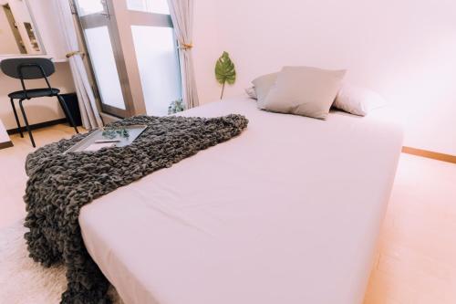 Una cama blanca con una manta encima. en Stylish Minimalist Loft 7 & Gym in Namba Compact Studio 5, en Wada