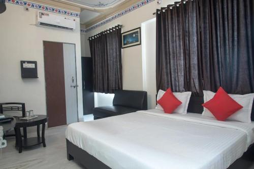 a bedroom with a bed with red pillows and a chair at HOTEL ARAWALI UDAIPUR CITY BEST couples friendly stay in Udaipur
