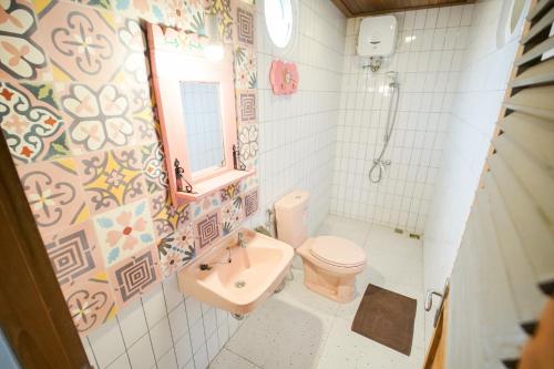 une salle de bain avec un lavabo, des toilettes et un miroir dans l'établissement Pilar Guest House Jogja, à Ngemplak