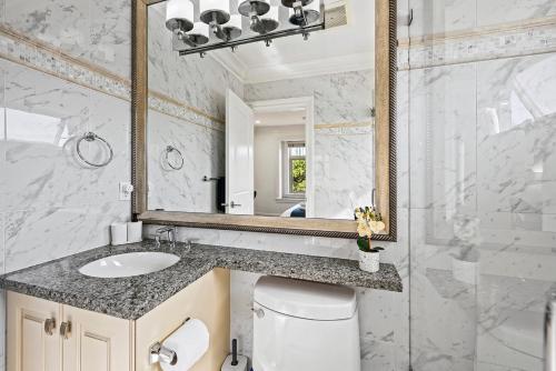 a bathroom with a sink and a mirror and a toilet at 1 Bedroom Luxury Retreat in Prime Vancouver in Vancouver
