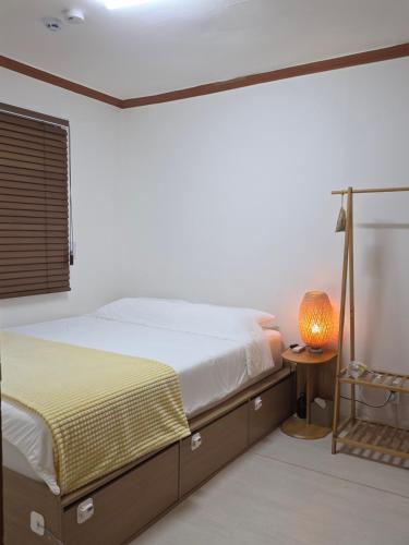 a bedroom with a bed and a lamp on a table at Stay EROB in Seoul