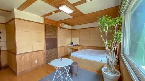 a small bedroom with a bed and a table at Backpacker's Home in Seogwipo